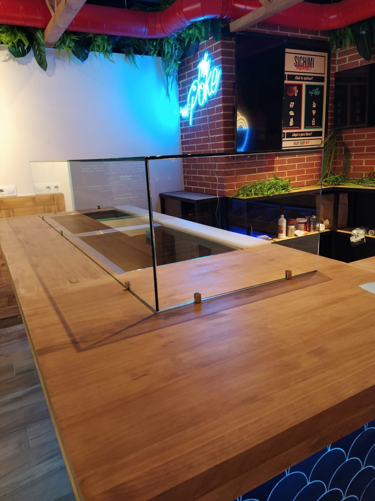 Una encimera de madera con un divisor de vidrio en un restaurante.