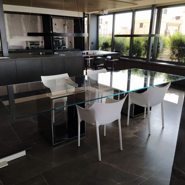 Un comedor con una mesa de cristal y sillas blancas.