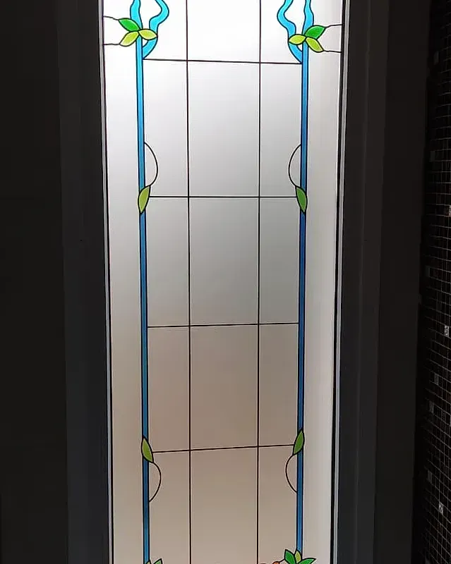 En un baño hay una vidriera con flores.