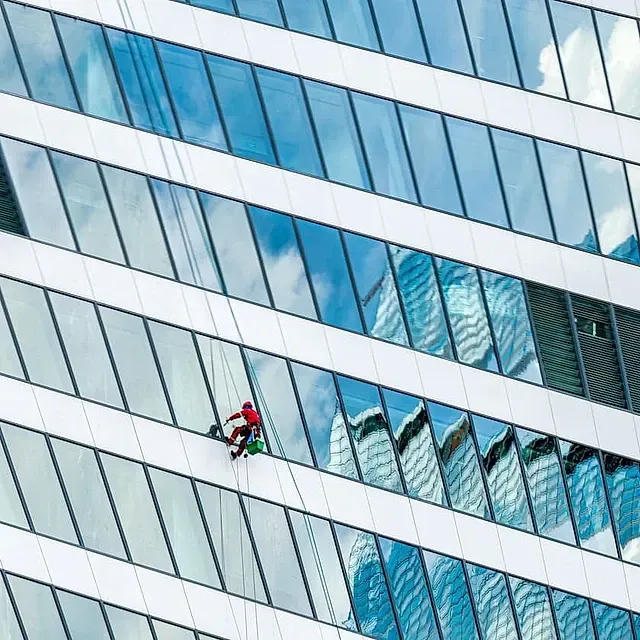 Un hombre está limpiando las ventanas de un edificio alto.