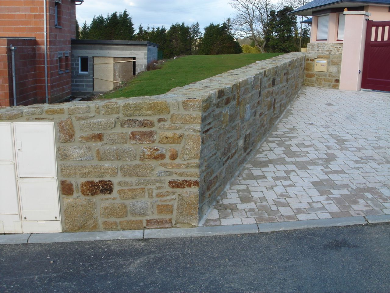 Muret en pierres avec intégration des coffrets et une boîte aux lettres