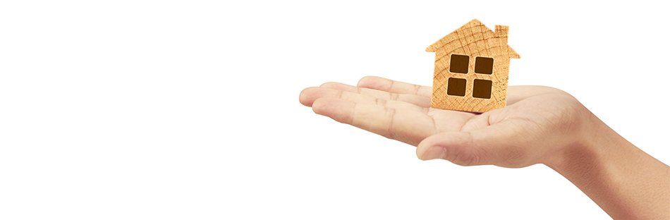 Main portant une maison miniature en bois