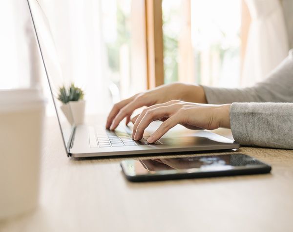 Mains de femme posées sur le clavier d'un ordinateur portable