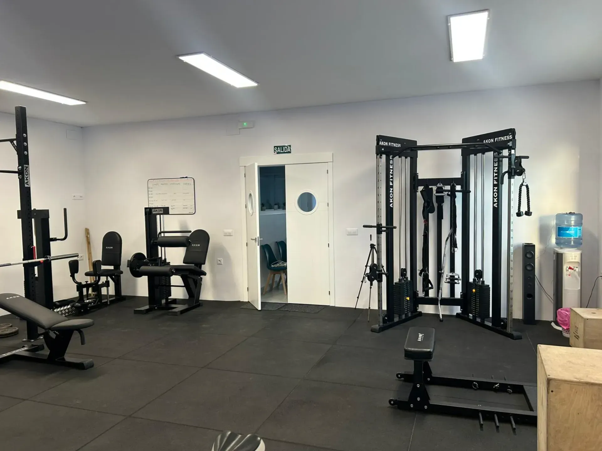 Un gimnasio lleno de muchos equipos de ejercicio y un dispensador de agua.