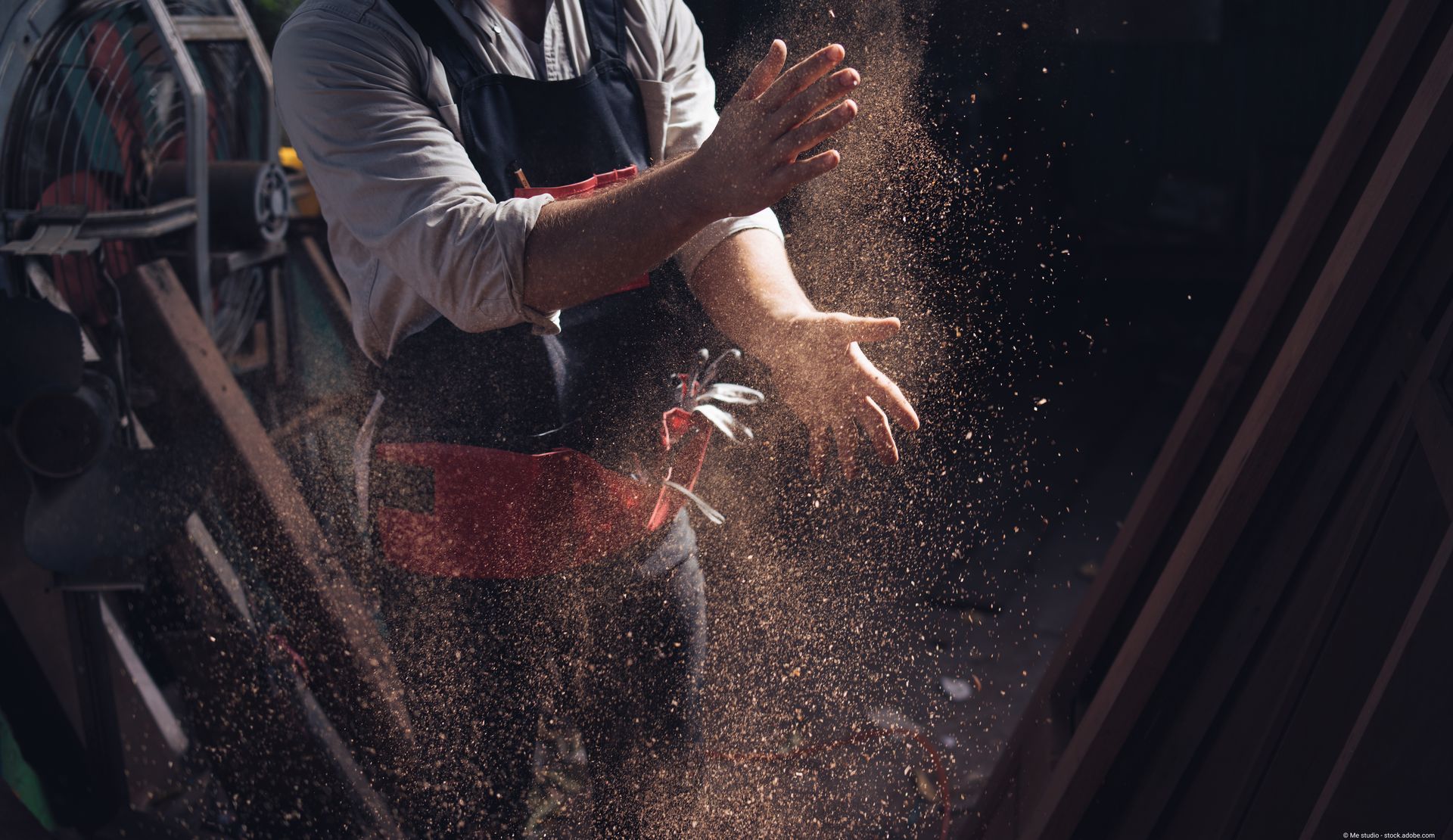 Ein Handwerker klatscht seine Hände sauber, damit die Sägespäne wegfallen
