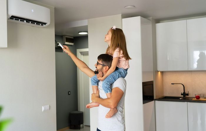 Un père et sa fille qui allument une clim