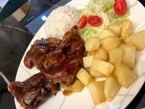 Plato de comida: carne estofada, arroz, patatas y ensalada con tomates.