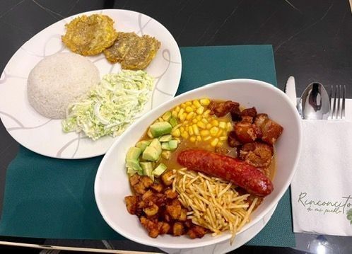 Dos platos de comida. Uno con arroz, ensalada y plátanos fritos. El otro con sopa, chorizo ​​y verduras.