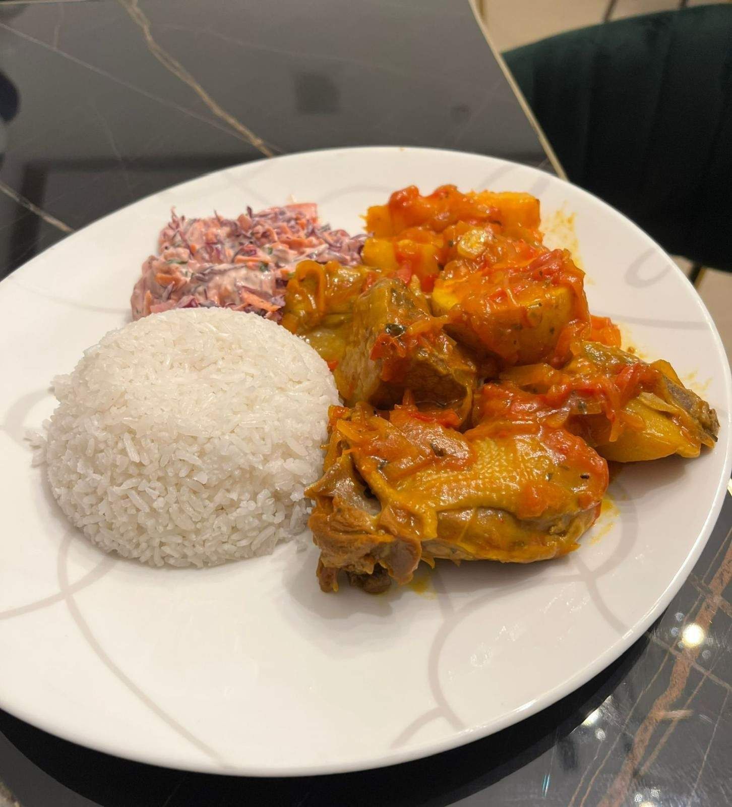 Plato de comida: arroz, pollo en salsa de tomate, ensalada de col.