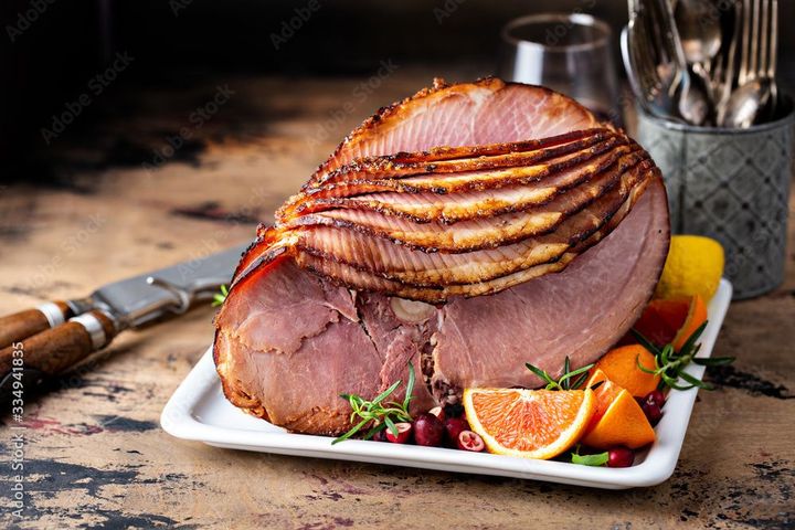 Une tranche de jambon est posée sur une assiette blanche sur une table.