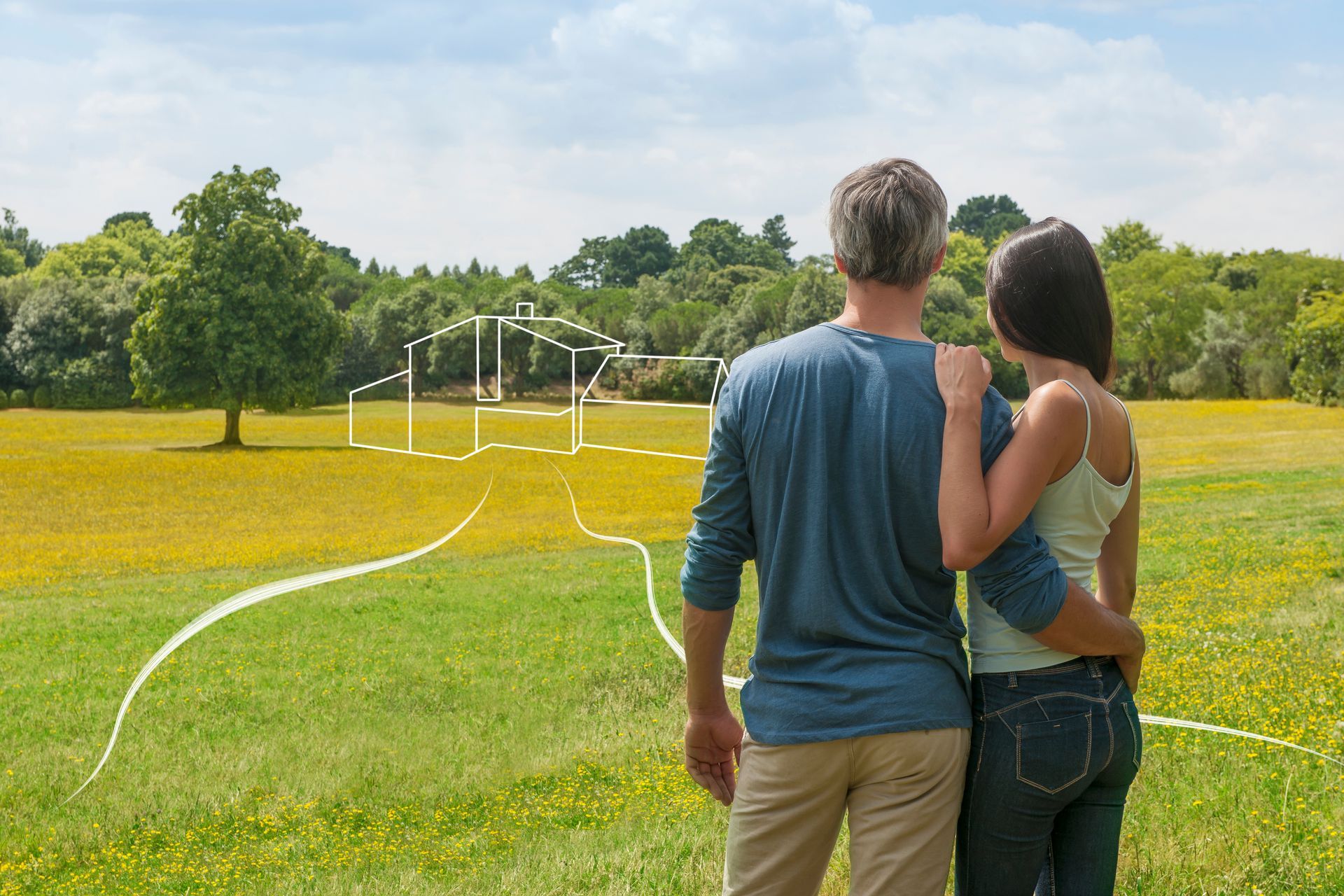 Un couple se tient debout dans un champ, avec le dessin de leur future maison