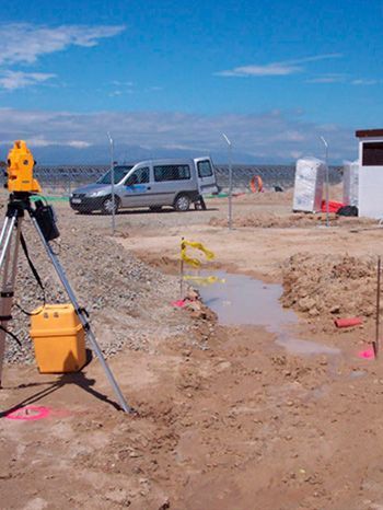 Una furgoneta blanca está estacionada al fondo de una obra en construcción.