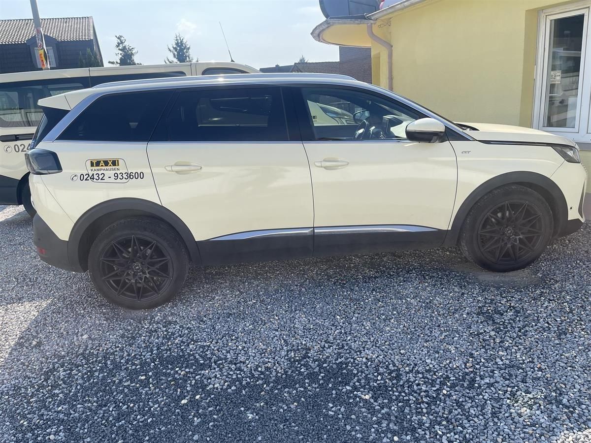 Weißer SUV seitlich auf einem Kiesweg neben einem gelben Haus geparkt