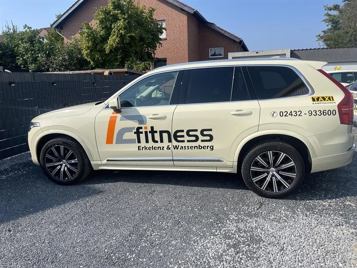 Beigefarbener SUV, der neben einem Haus auf einem Schotterplatz geparkt ist, mit Firmenlogo und Telefonnummer an der Seite