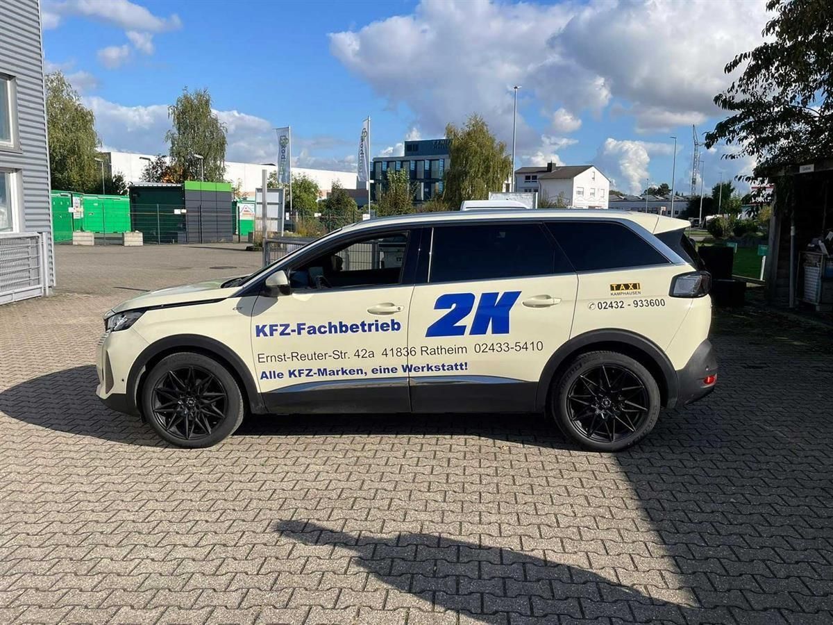 Cremefarbener SUV auf einem Kopfsteinpflasterplatz unter teilweise bewölktem Himmel