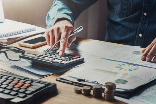 Un hombre está usando una calculadora y un bolígrafo en un escritorio.