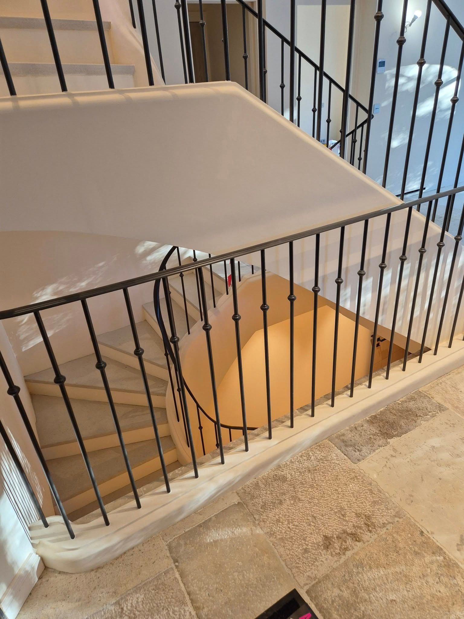 Escalier avec rambarde métallique noire et vue sur l'étage inférieur.