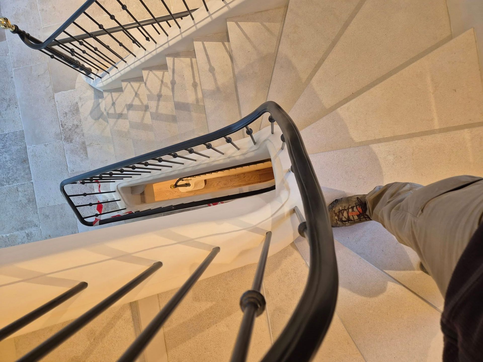 Vue en contrebas d'un escalier en colimaçon à rampe noire.