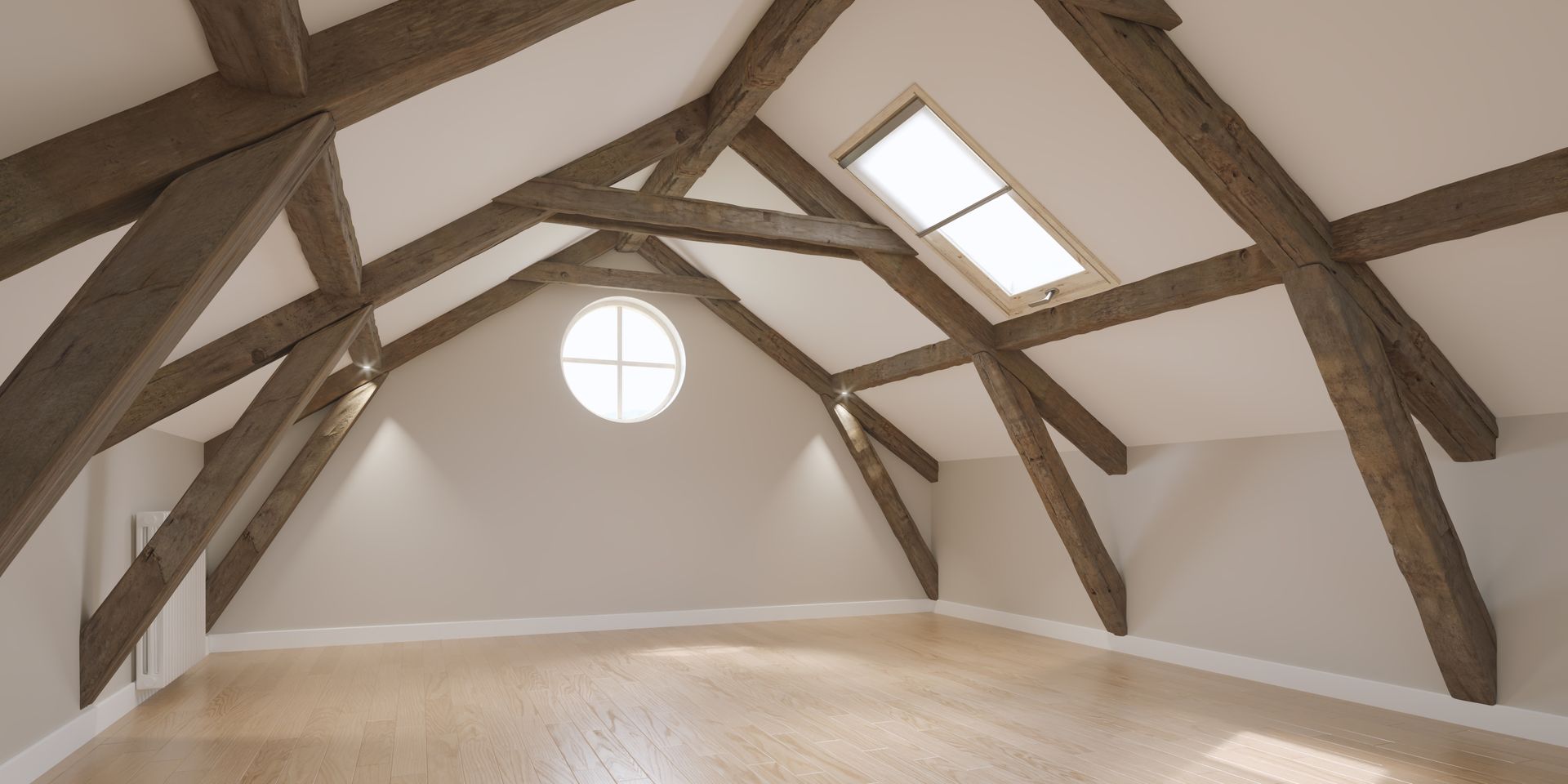 Intérieur mansardé avec poutres apparentes, puits de lumière et fenêtre ronde sur murs blancs.