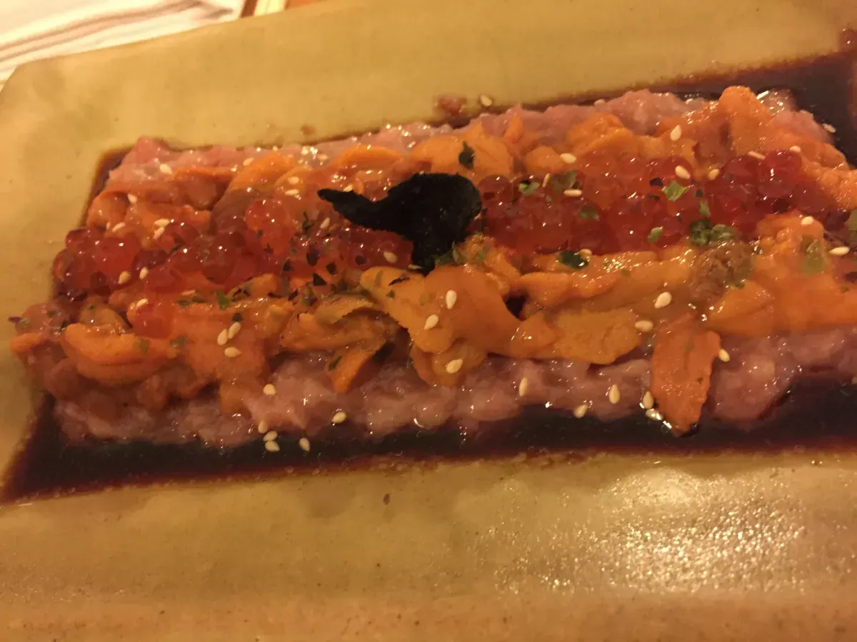 Plato de mariscos crudos con uni naranja, huevas de salmón y semillas de sésamo