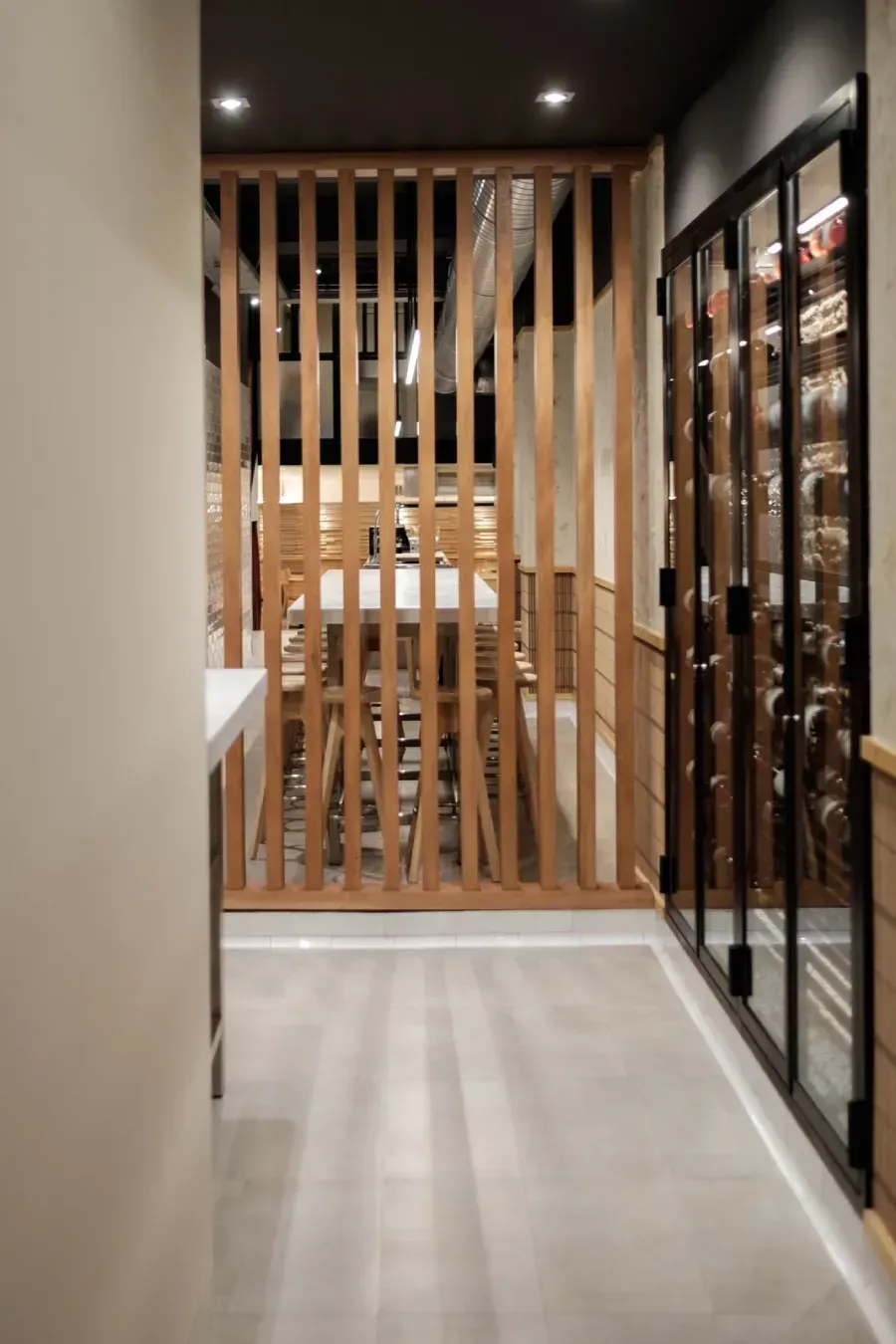 Divisoria de listones de madera y bodega con puerta de cristal en un pasillo moderno.