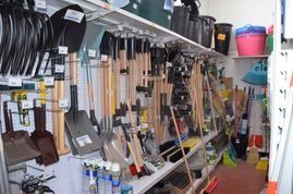 Estanterías de una ferretería repletas de herramientas de jardinería, como palas, rastrillos y escobas.