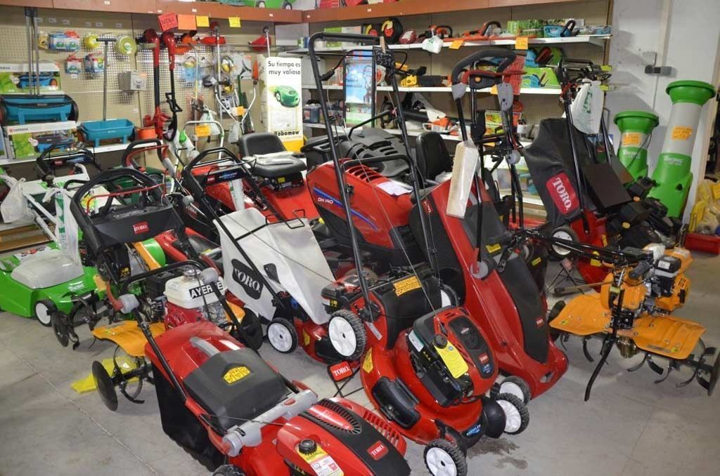 Una exhibición de cortadoras de césped y herramientas eléctricas para exteriores de varios colores rojo, blanco y amarillo dentro de una tienda minorista.