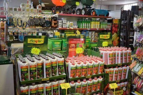 Estanterías de una tienda repletas de diversos productos de jardinería, incluyendo botellas de fertilizante y guantes de trabajo.