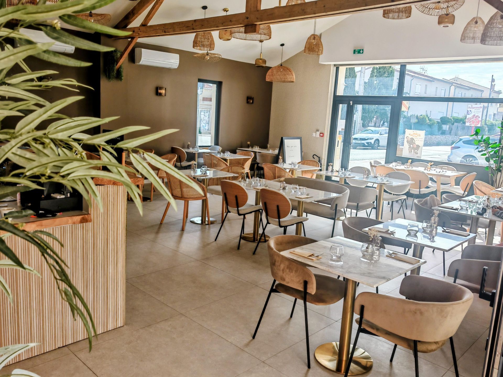Salle à manger moderne et lumineuse d'un café avec tables en bois, chaises en osier et grandes fenêtres