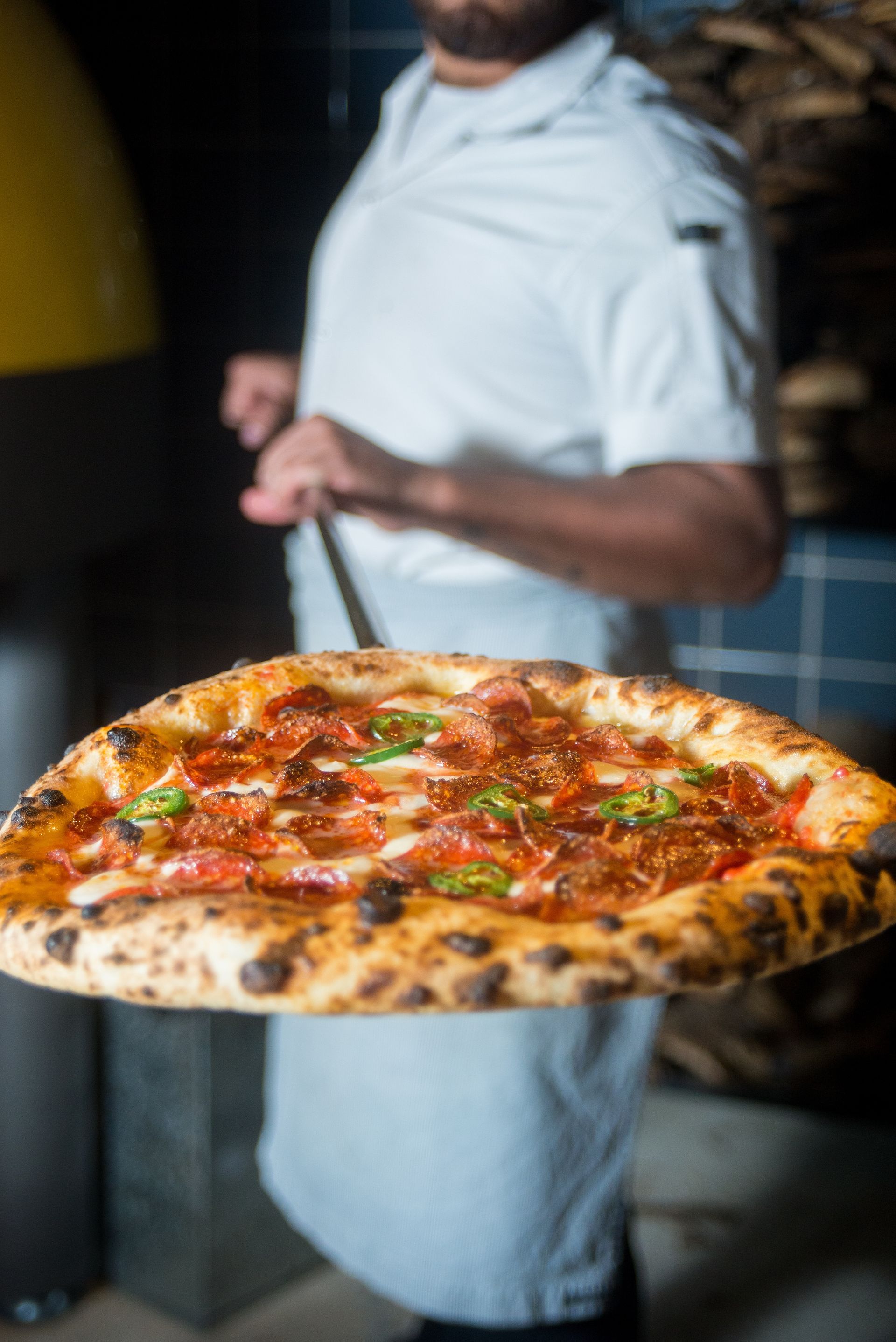 Une personne transportant une grande pizza pepperoni sur un plateau dans un restaurant