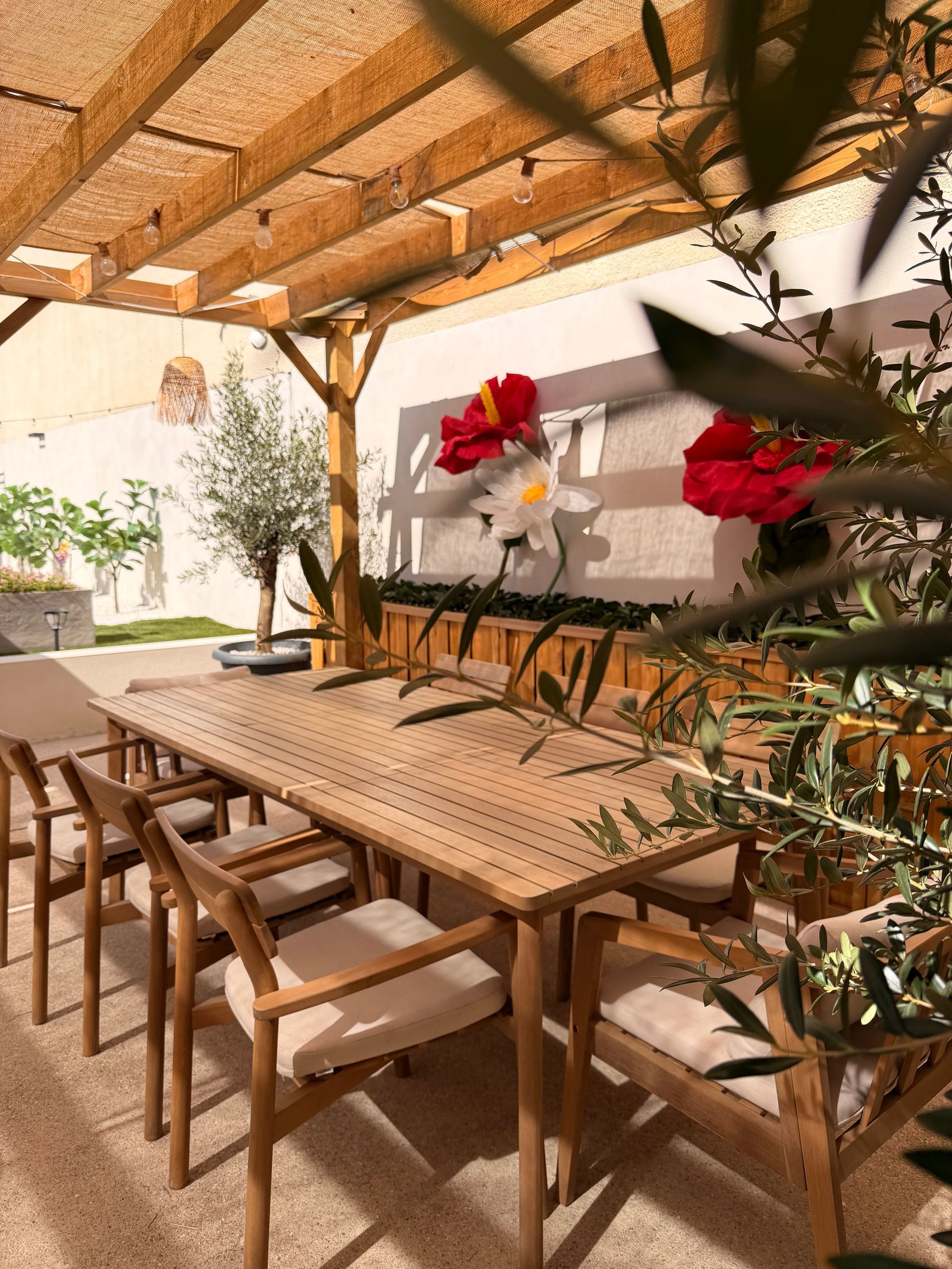 Table à manger extérieure couverte avec chaises en bois et composition florale sur une terrasse