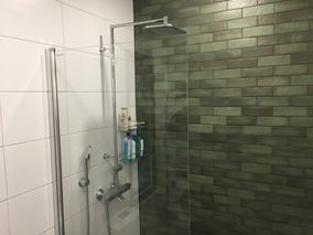 Suihku tummalla seinälaatoituksella