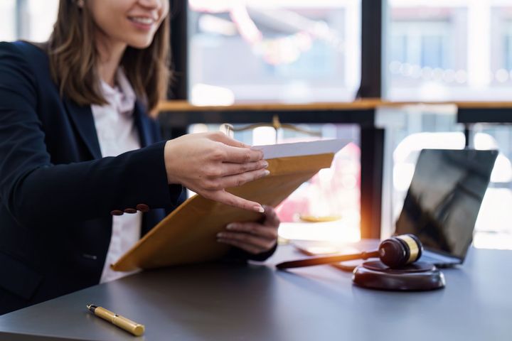 Una mujer está sentada en un escritorio con una computadora portátil y un mazo.