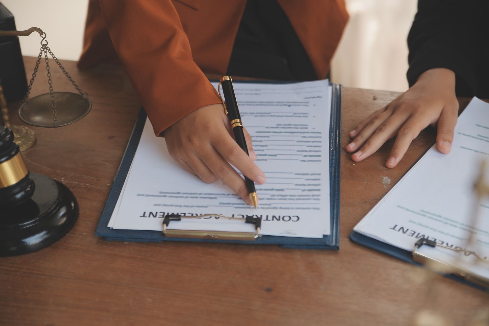 Una persona está firmando un contrato en un portapapeles con un bolígrafo.