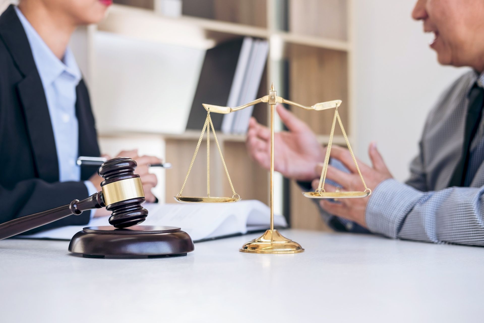 Un hombre y una mujer están sentados en una mesa con una balanza de justicia y un mazo de juez.