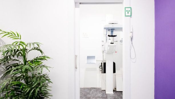 Un consultorio dental con una planta y una máquina de rayos X.