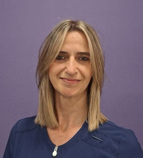 Una mujer con una blusa azul sonríe para la cámara.