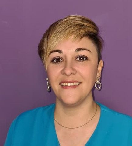 Una mujer con camisa azul y pendientes sonríe a la cámara.
