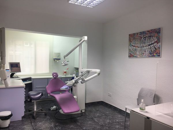 Un consultorio dental con una silla morada y un cuadro en la pared.
