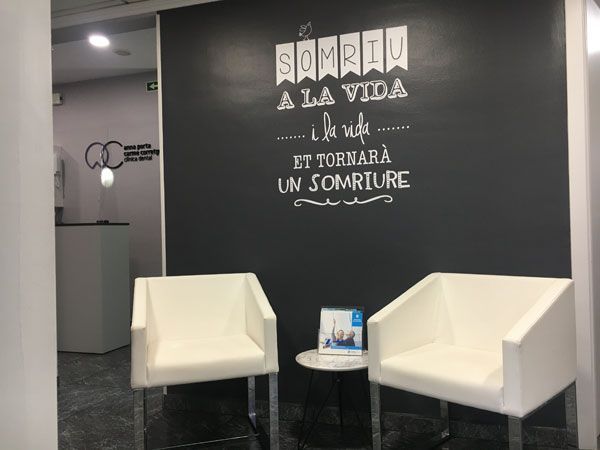 Dos sillas blancas frente a una pared que dice somriu a la vida