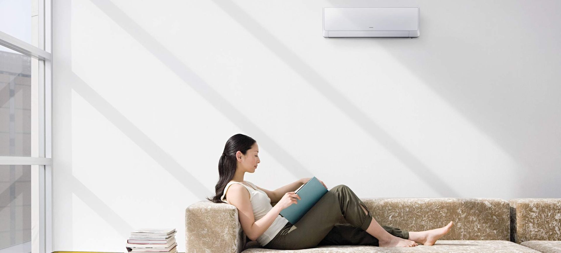Femme lisant sur le canapé sous le climatiseur