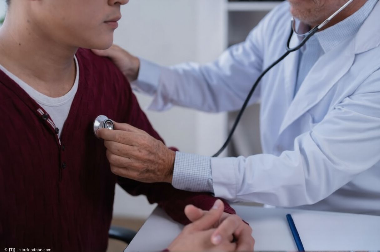 Ein Arzt untersucht in einer Klinik mit einem Stethoskop den Brustkorb eines Patienten.