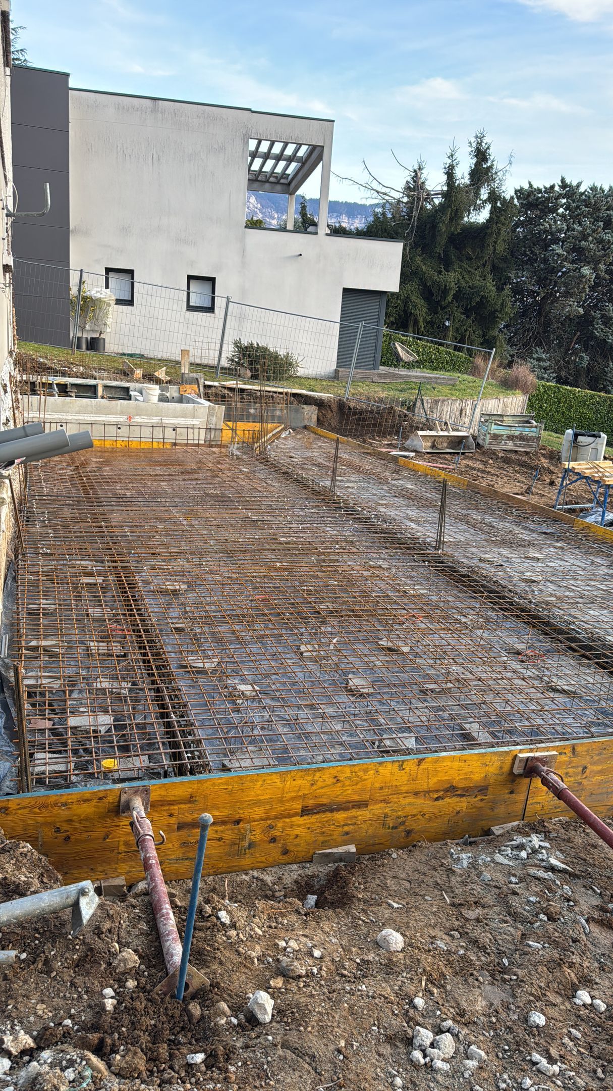 Grille d'armature en béton armé sur un chantier de construction avec un bâtiment.
