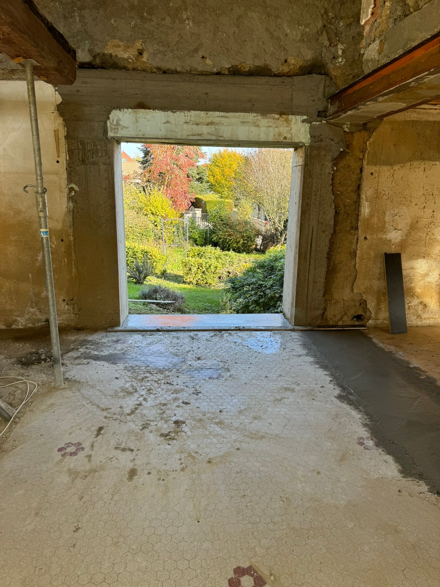 La rénovation d'une pièce montre une ouverture de porte avec une poutre jaune et des travaux de plâtre nouvellement installés.