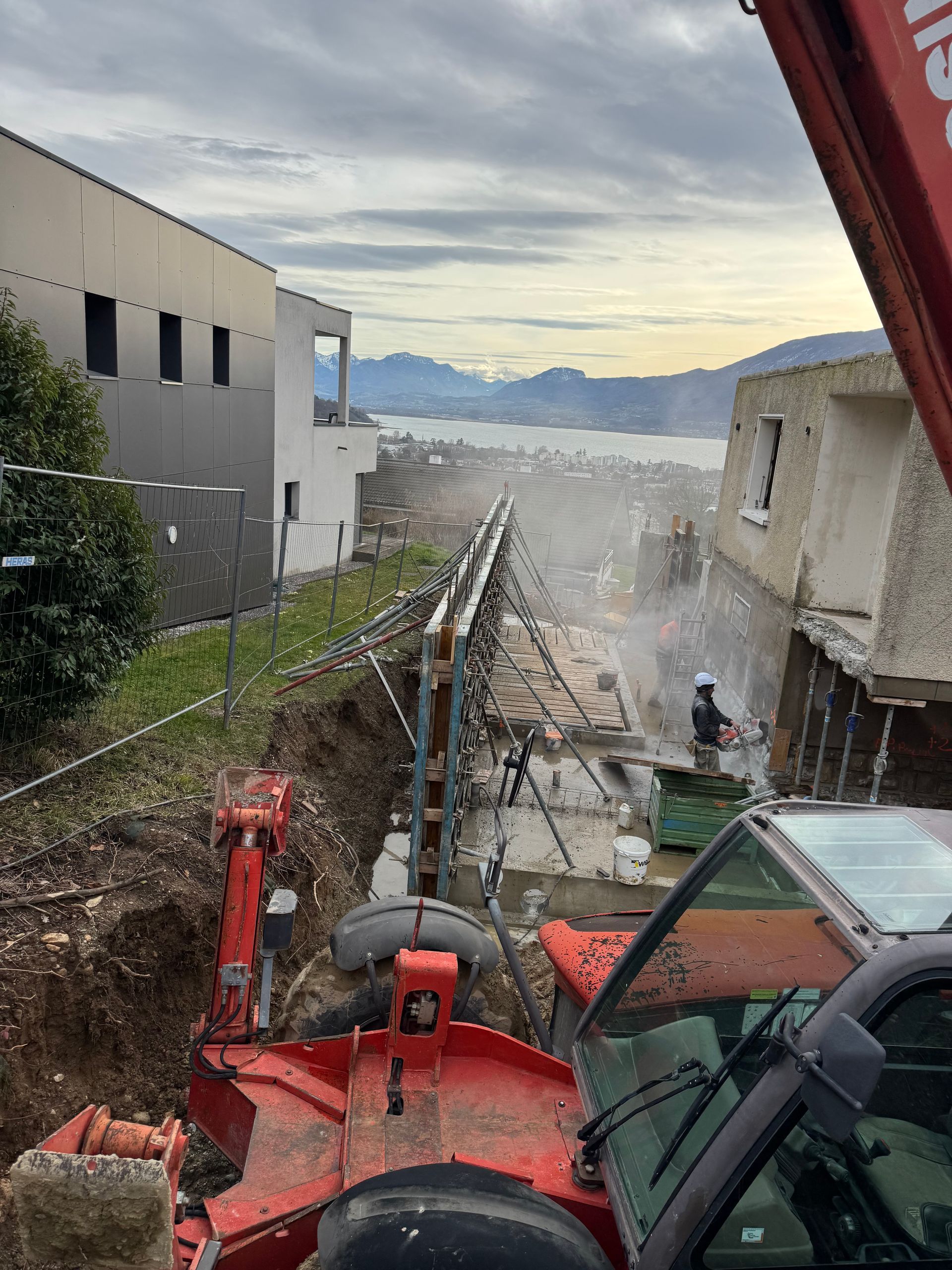 Un ouvrier utilise un outil électrique sur une fondation en béton, sur un chantier de construction.