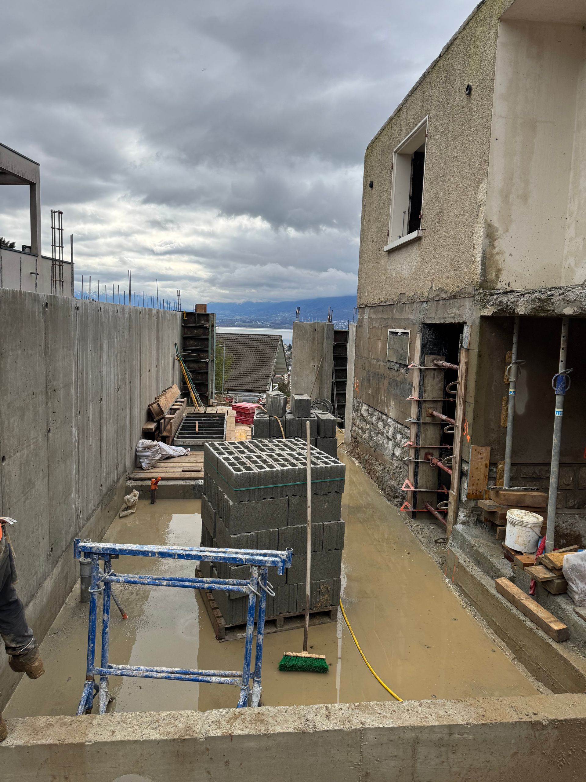 Allée de chantier longeant des bâtiments inachevés.
