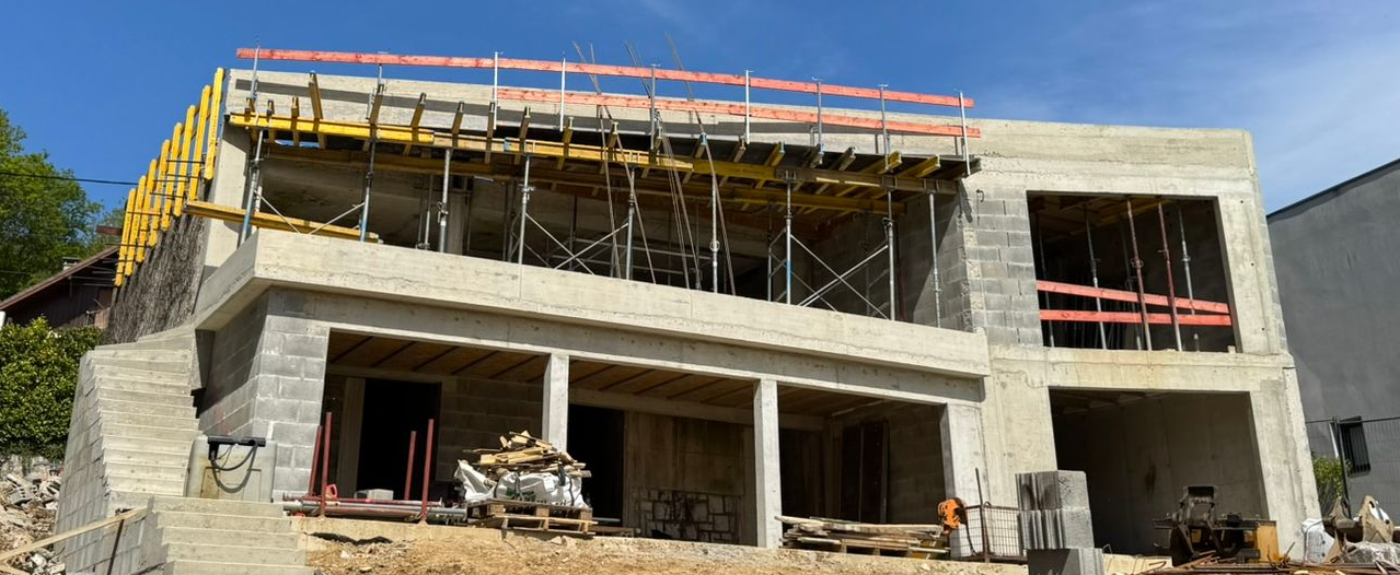 Un bâtiment de deux étages en construction, avec des murs extérieurs, des ouvertures de fenêtres.