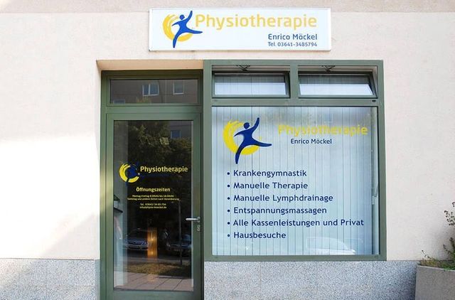 Außenansicht einer Physiotherapiepraxis mit Glastür und Fensterbeschilderung an einer hellen Gebäudefassade