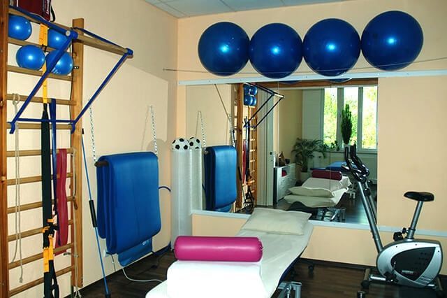 Physiotherapieraum mit Gymnastikbällen, Behandlungsliege, Spiegeln und Fitnessgeräten