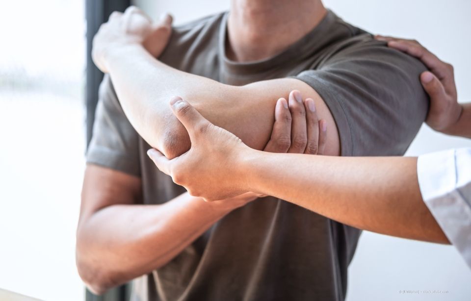 Physiotherapeut dehnt den Arm eines Patienten während einer Rehabilitationssitzung